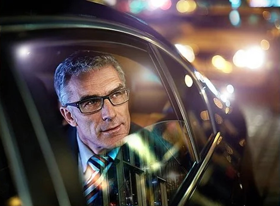 Ein Mann im Auto, umgeben von nächtlichen Lichtern